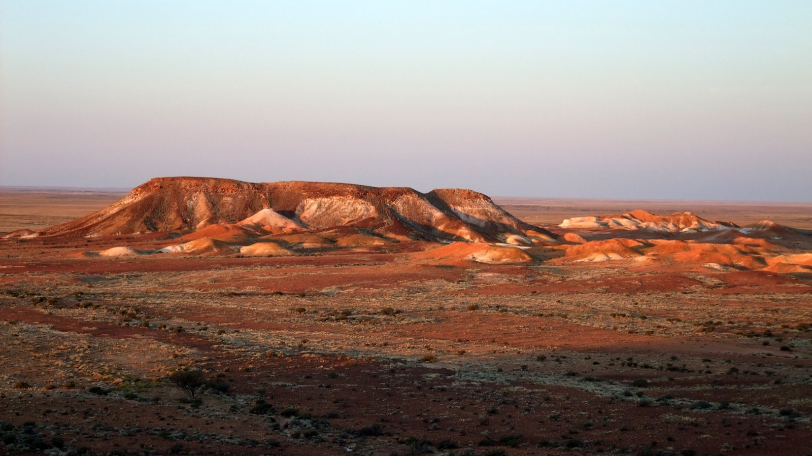 The copper and white ridges of Kanku-Breakaways beneath a vast evening sky
