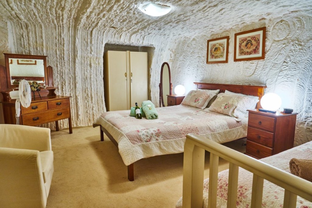 A warm bedroom carved into pale sandstone underground